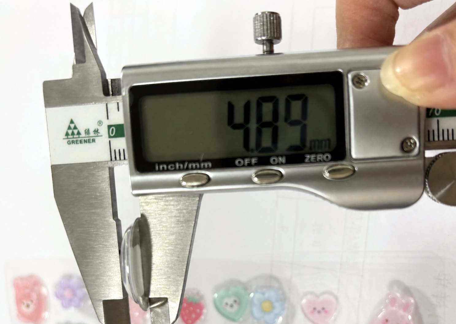 製造工場の実物サンプルの盛り高さをノギスで測っているところ。表示は4.89mm
